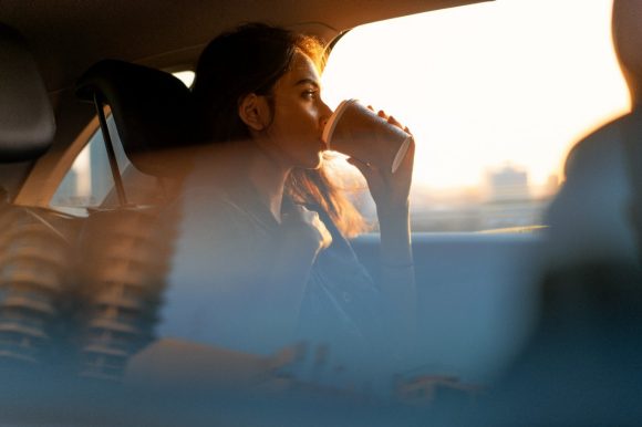 Woman in car drinking coffee