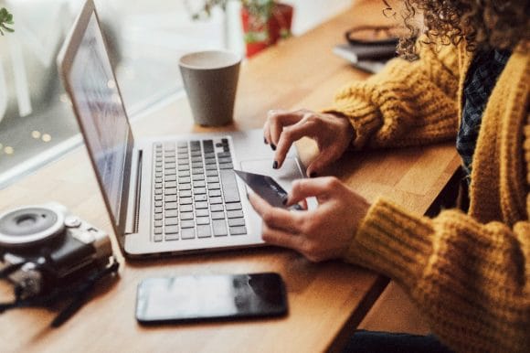 Eine Frau sitzt mit ihrem Laptop und gibt Daten ins E-Banking ein