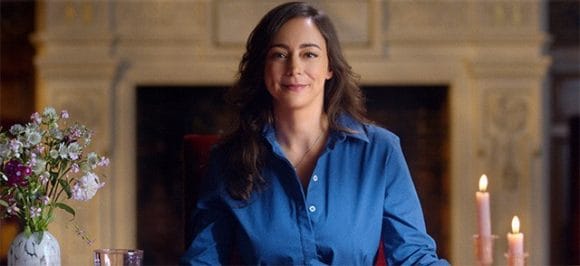 A woman sitting at a table looking into the camera.