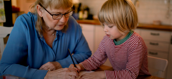 Dame âgée aidant un enfant à étudier à la maison.