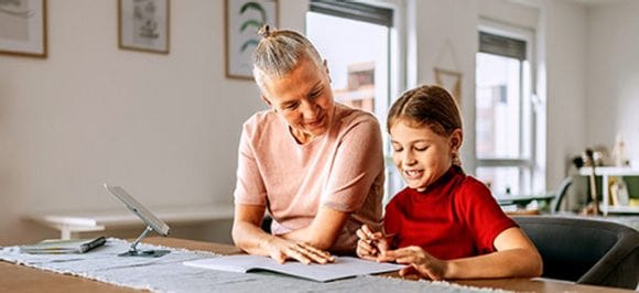 Signora anziana che aiuta un bambino a studiare a casa.