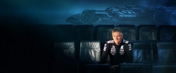 Sitzender Mann, mit Bild eines Autos im Hintergrund