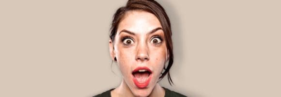 A woman looks at the camera with surprise.