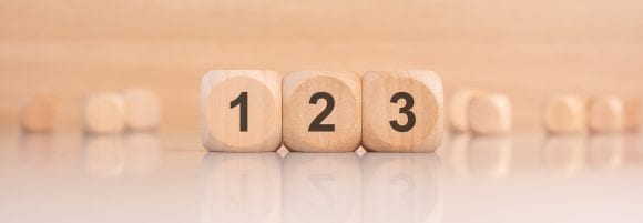 Three light brown wooden cubes numbered 1, 2 and 3 sit on a plain background.