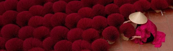 Female worker in Asia clad in red arranging a large number of bunches of red plants.