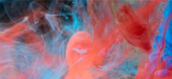 L'immagine mostra liquidi rossi e blu che si mescolano nell'acqua, creando motivi e sfumature di colore affascinanti – un motivo artistico e dinamico.