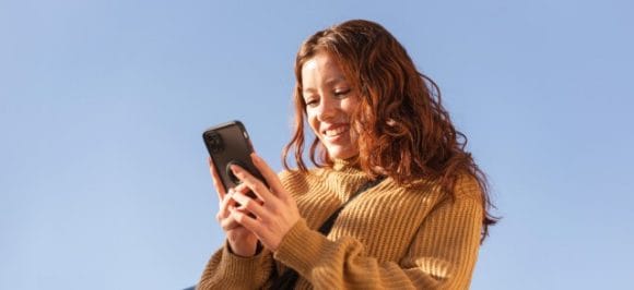 Giovane donna che guarda il suo smartphone.