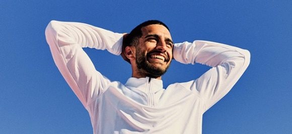 Una giovane donna con gli occhiali da sole ride e gioca con la neve.