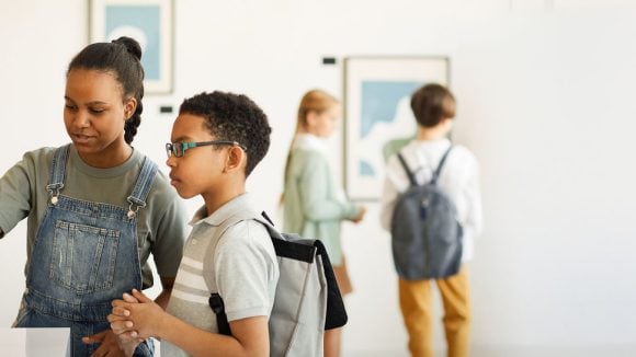 Group of diverse school-age children at an art museum interacting with an art display.