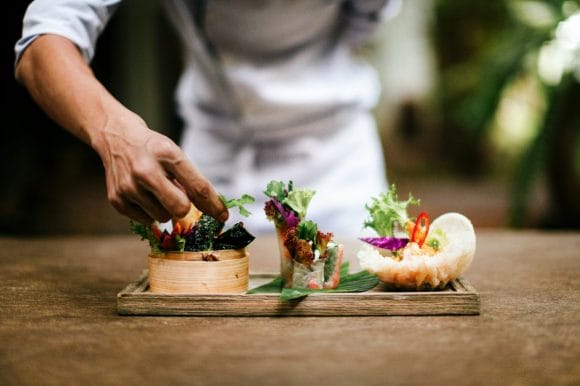 Chef finishing dish with salads and spring rolls