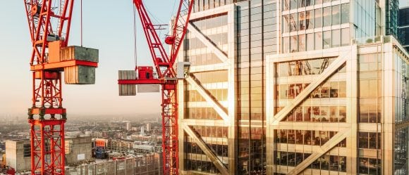 Construction cranes in front of skyscraper