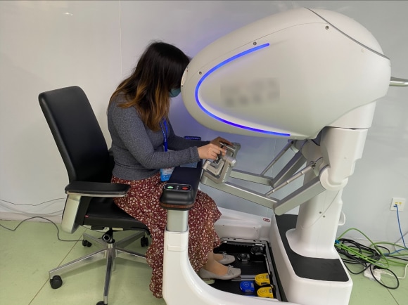image 1 : Healthcare analyst Cui Cui is trying out a Chinese-made surgical robot during a company visit.