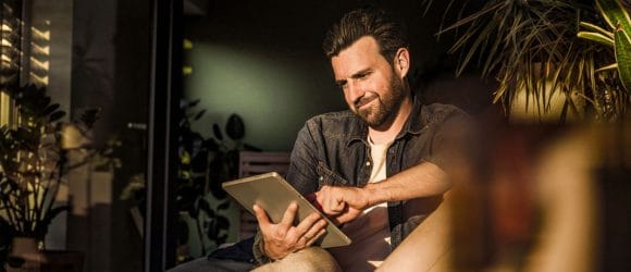 Men watching tablet seating on sofa