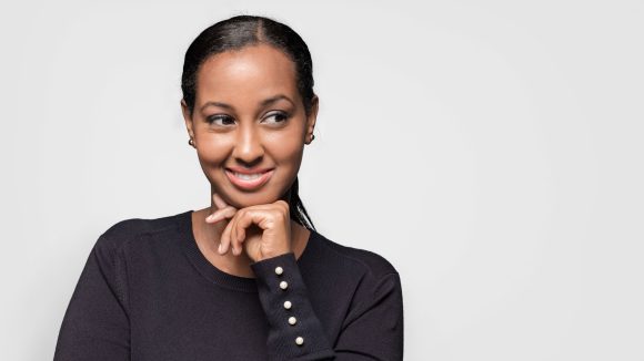 Smiling young woman looking sideways while leaning on her fist.