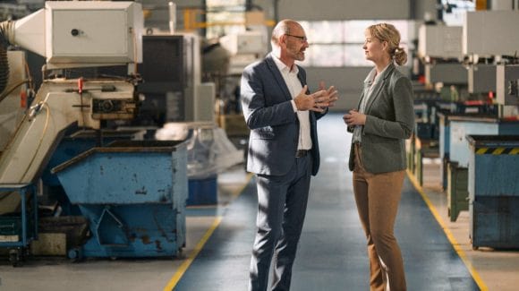 Two business people having conversation in factory hall