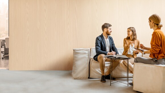 Un homme et une femme discutent de choix financiers avec un stratège dans un bureaux.