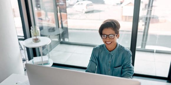 Young entrepreneur smiling while looking at her desktop computer