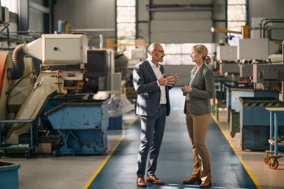 Two business people having conversation in factory hall