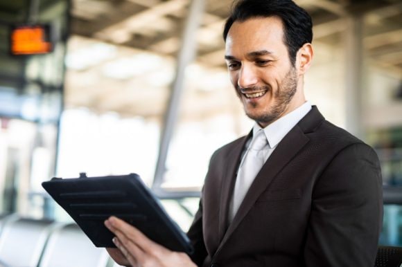Ein Mann lächelt, als er auf sein Tablet schaut.