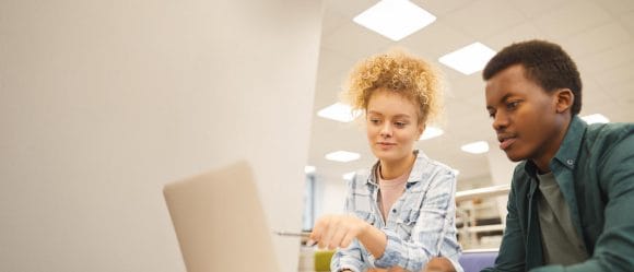 Zwei junge Menschen sitzen am Laptop