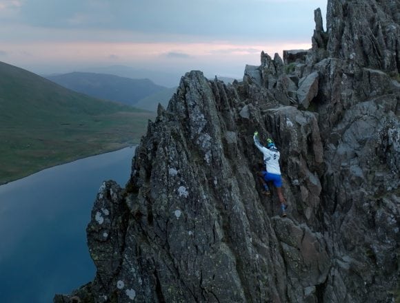 Jeev climbs in a blue and white outfit navigates steep, rocky terrain