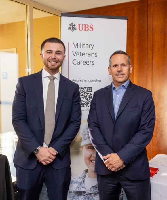 Two UBS employees standing in front of a Military Careers sign at a Veteran recruitment event.