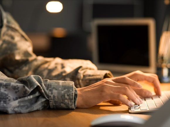 someone in uniform typing at a computer