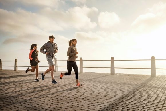 Three people running on a pier