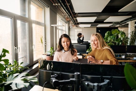 Two colleagues sitting in front of computer screens