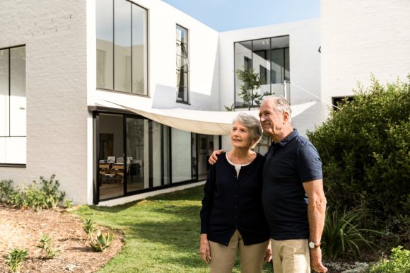 Elderly couple standing in the garden outside their home