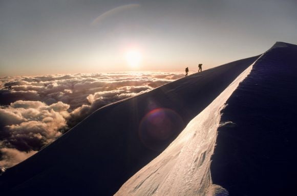 two guys climbing a mountain peak