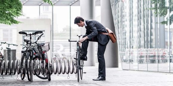 A man in a suit puts his bike off.