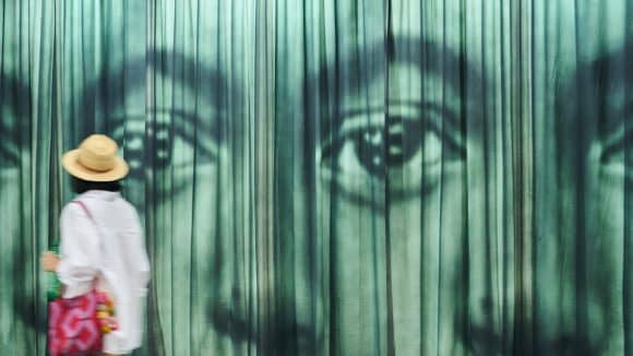 A person looking at a curtain with eyes on it