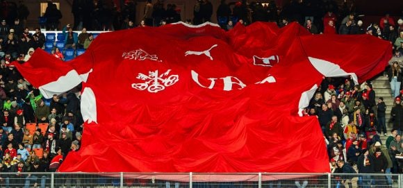 Fans holding giant Red Bull banner in stadium