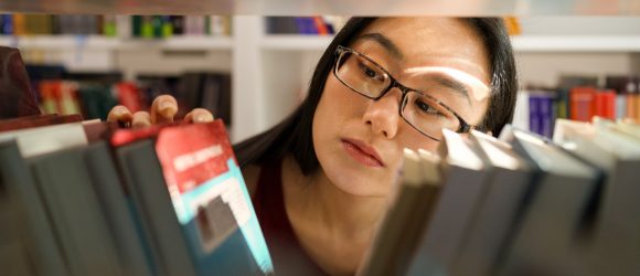 Woman searching through bookshelf