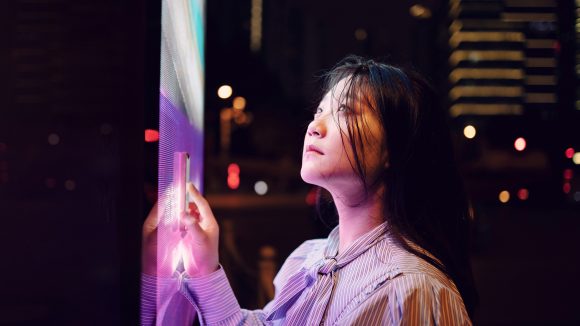 A young woman looking at a digital see through screen