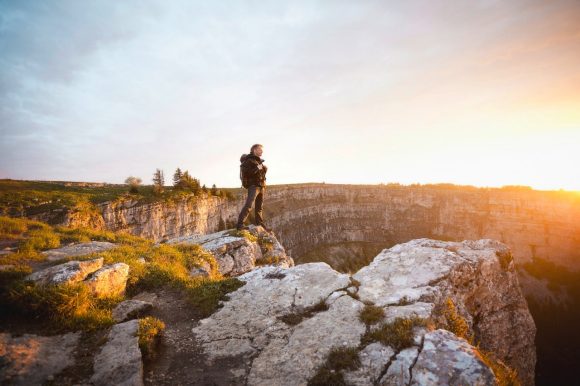 Hiker standing on mountain cliff at sunset, Switzerland