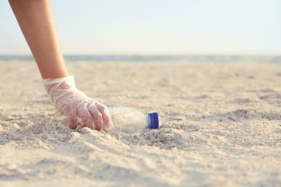 A person is picking empty bottle on the beach