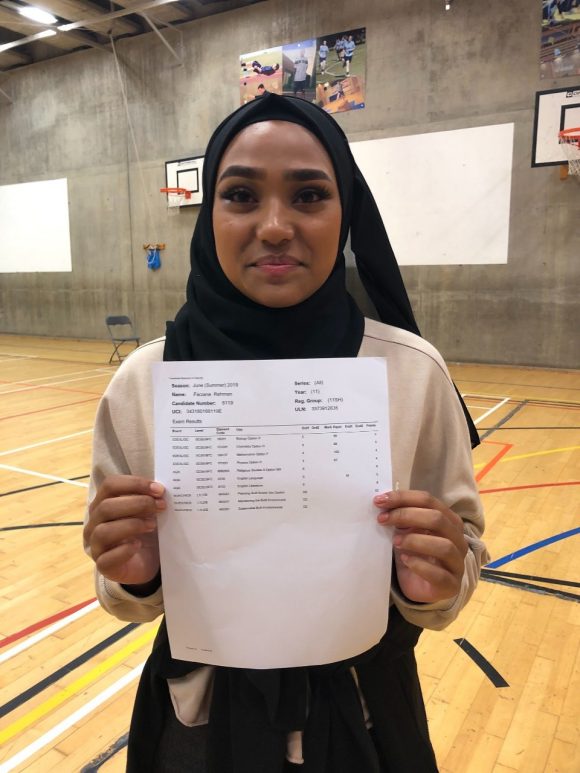 Young female student holding up paper with exam results