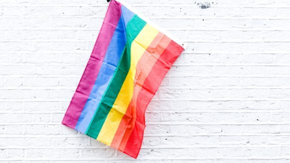 Rainbow colored flag against a white wall