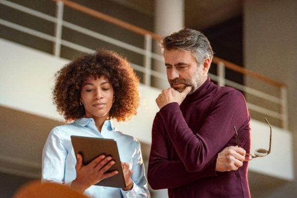 Businesswoman sharing tablet with colleague