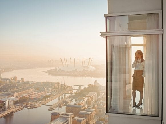 A women speakig on phone while standing in office balcony