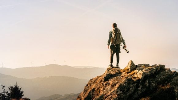 Hiker looking at wind power station in distance