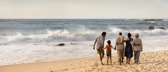 Three generation family walking on beach