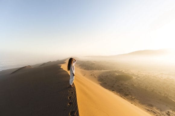 Woman on sand dune at sunrise
