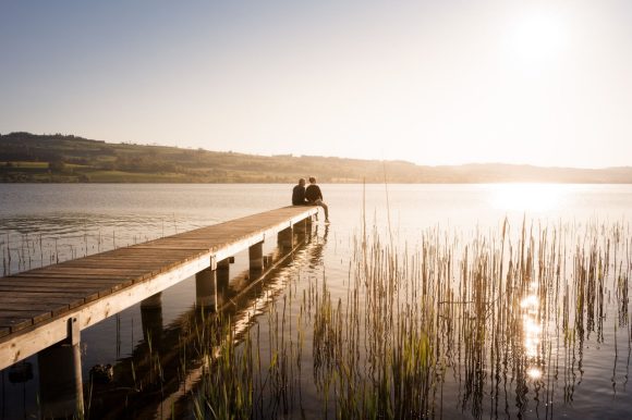 Pareja sentada en un muelle junto al lago