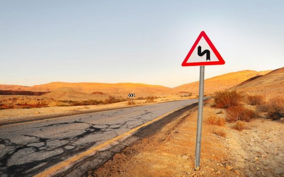 Señal de curva en una carretera desértica