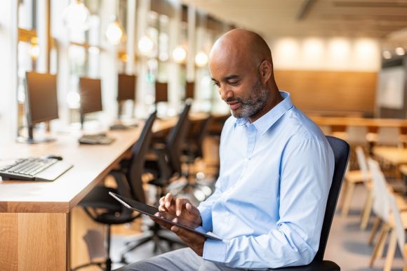 Hombre trabajando en una tableta en un área de oficina compartida.