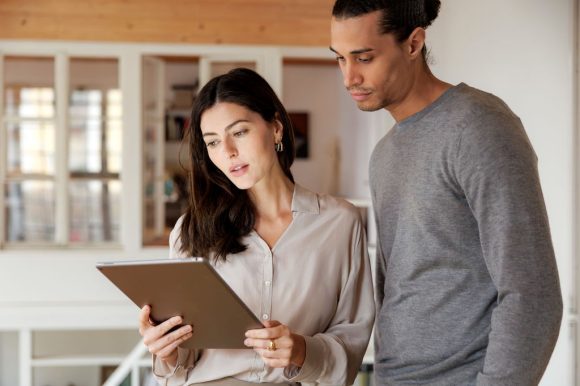 Hombre y mujer revisan información en una tableta en un entorno de oficina.