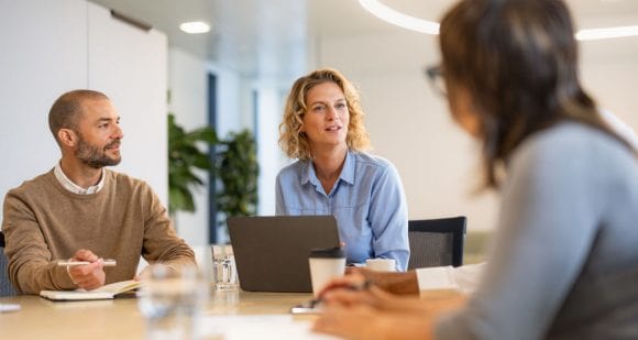 Equipo de trabajo colaborando en una mesa con computadora portátil